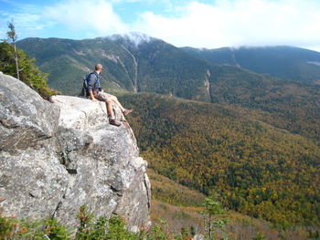 Man standing on rock by land against mountains