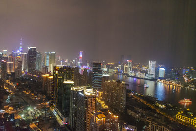 Illuminated buildings in city against sky at night