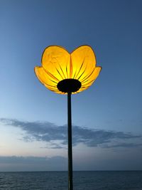 Street light by sea against blue sky