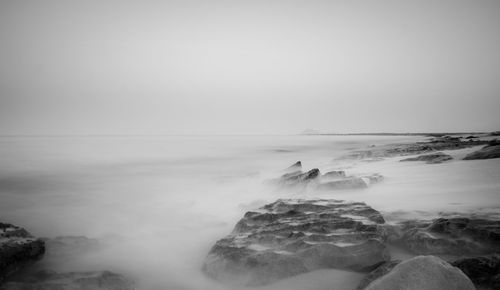 Scenic view of rocks in sea against sky