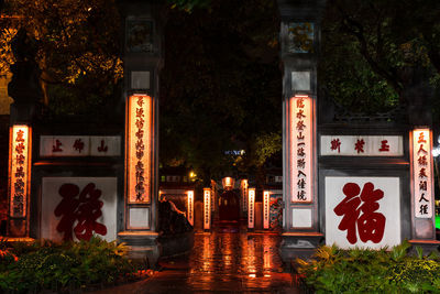 Illuminated building by trees at night