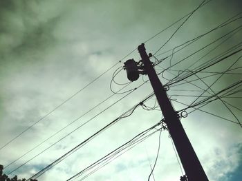 Low angle view of silhouette electricity pylon against sky