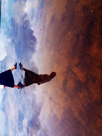Silhouette of woman standing against cloudy sky