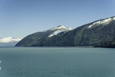 Scenic view of sea and mountains against clear blue sky