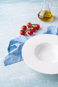 Empty plate for serving pasta or soup, on blue background with blue dining cloth