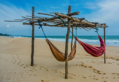 Wooden posts on beach against sky