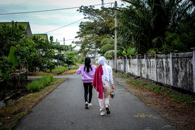 Rear view of women walking on footpath