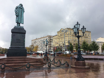 Statue in city against cloudy sky