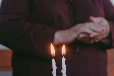 Midsection of person standing by candles