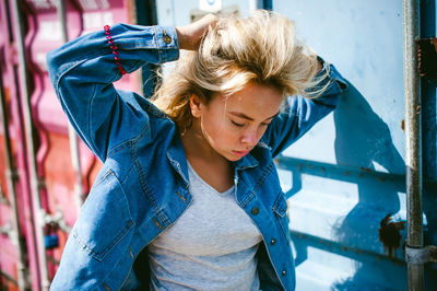 Young woman wearing denim jacket against metal structure