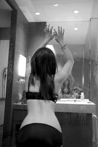 Rear view of woman standing in bathroom