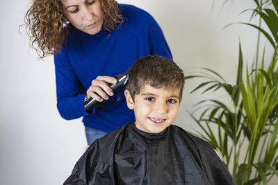 Funny boy getting haircut at home with scissors