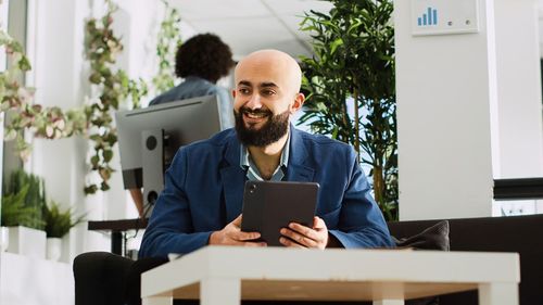 Young man using digital tablet while sitting on table