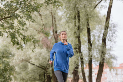 Portrait of woman standing against trees