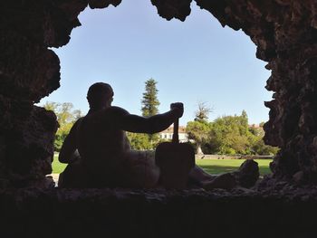 Men sitting on rock against sky