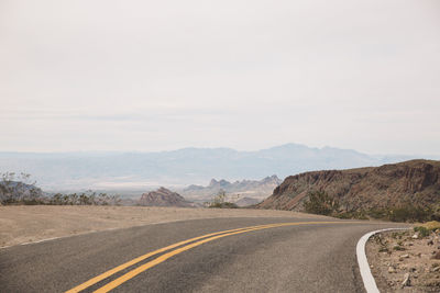 Scenic view of road by mountains against sky