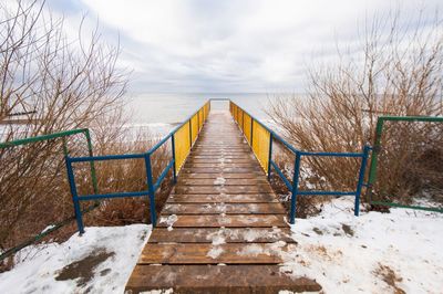 Pier over sea against cloudy sky during winter