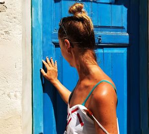 Rear view of woman standing against blue door