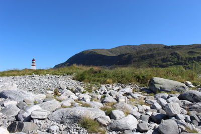 Rocks on land against clear blue sky