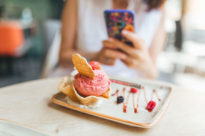 Midsection of person holding ice cream cone on table