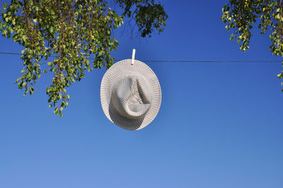Low angle view of sun hat drying on clothesline against clear sky