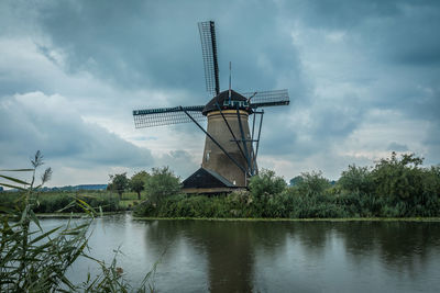 Lake by traditional windmill against sky