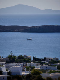 High angle view of sailboats sailing on sea by buildings against sky