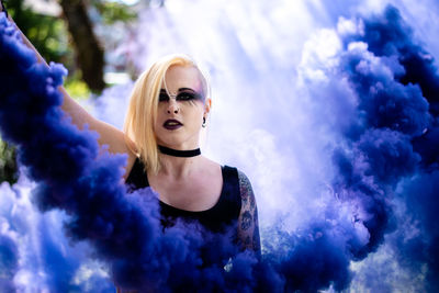 Portrait of beautiful woman with spooky make-up holding distress flare