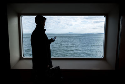 Man looking at sea seen through window