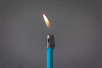 Close-up of burning candle against black background