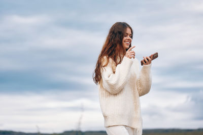 Young woman standing against sky