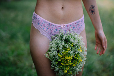 Midsection of woman standing by flowering plant