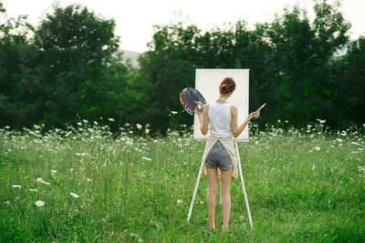 Rear view of woman with umbrella standing on field