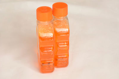 Close-up of orange bottle on table against white background