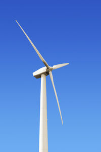 Low angle view of windmill against clear blue sky