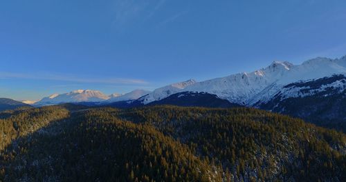 Scenic view of snowcapped mountains against blue sky