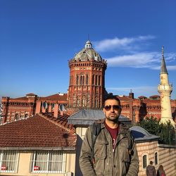 Portrait of young man standing against buildings