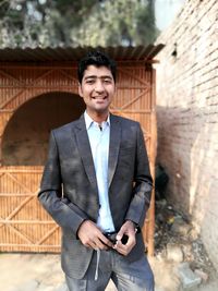  portrait of young man wearing blazer standing outdoors