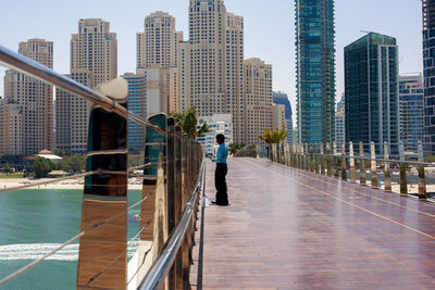 Rear view of man walking by modern buildings in city