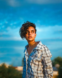 Portrait of young man standing against blue sky