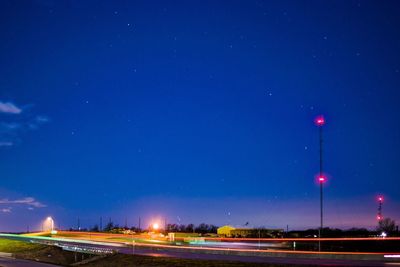 Light trails on road against blue sky at night