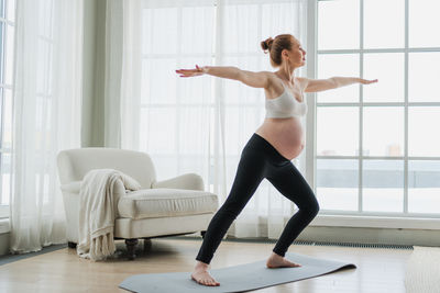 Full length of young woman exercising at home