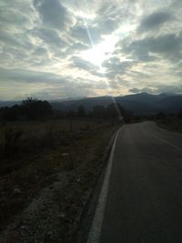 Empty road along landscape at sunset