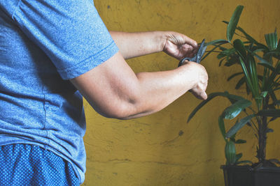 Midsection of man holding yellow wall