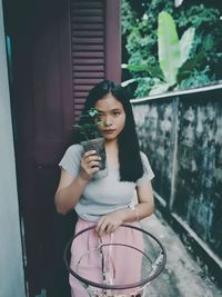 Portrait of a beautiful young woman standing against wall