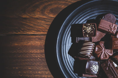 Pralines on plate on wooden base, deep shadows, close up. sweet and chocolate concept.