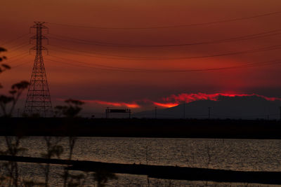 Silhouette electricity pylon against romantic sky at sunset