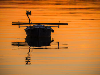 Silhouette boat in sea against orange sky