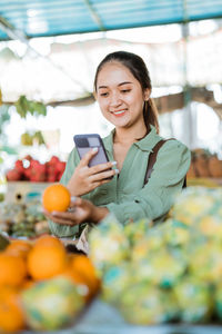 Portrait of smiling young woman holding fruits at home