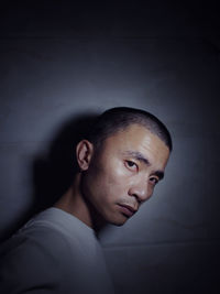 Portrait of sad man standing against wall in darkroom
